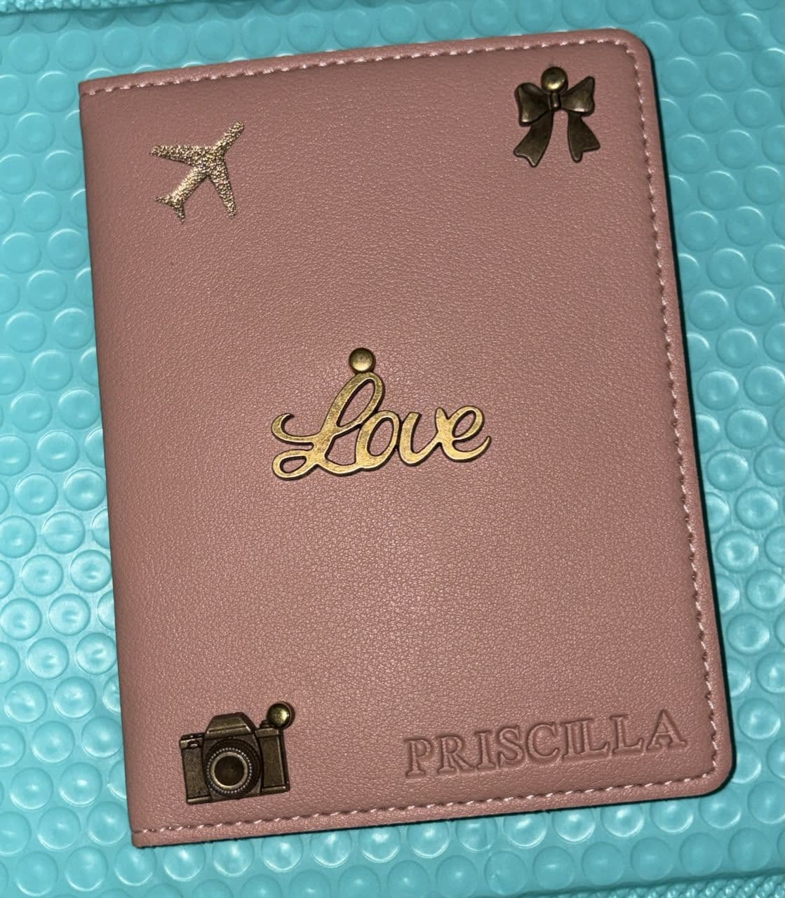 Personalised mauve passport cover with a gold Love script, bow and camera charms, embossed PRISCILLA